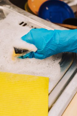 Sarı süngerler ve bulaşık deterjanı kirli lavaboda bulaşık ve mutfak malzemeleriyle dolu..