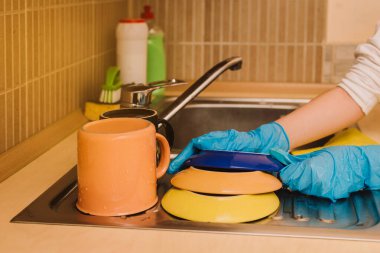 Mavi lastik eldivenli ellerin yıkandığı yakın çekim görüntüsü. Mutfakta lavaboyu yıkayan kadın elleri. Mutfaktaki lavabonun üzerinde ev işi yapan kadın eller. Anneler günün kutlu olsun.