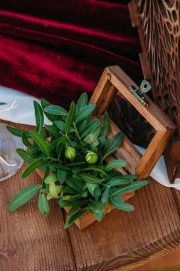 Nikah töreni sırasında tahta bir masanın üzerinde çiçeklerle süslenmiş alyanslar için bir kutu. Düğün süslemeleri. Bir düğün dekorunun yakın çekim detayları