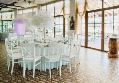 Çiçek süslemeleri ve mumlarla çok güzel bir düğün masası. Kapalı alanda düğün töreni. Bir düğün dekorunun yakın çekim detayları