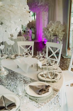 Çiçek süslemeleri ve mumlarla çok güzel bir düğün masası. Kapalı alanda düğün töreni. Bir düğün dekorunun yakın çekim detayları