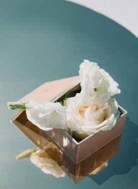 Alyanslar çiçek aranjmanıyla süslenmiş tahta bir kutuda duruyor. Açık havada düğün töreni. Bir düğün dekorunun yakın çekim detayları