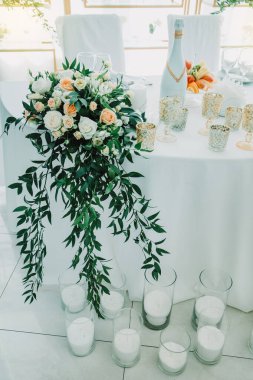 Gelin ve damadın düğün masası çiçeklerle ve mumlarla süslenmiş. Kapalı alanda düğün töreni. Bir düğün dekorunun yakın çekim detayları