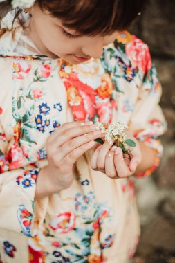 Elinde çiçek açan bir spireanın güzel bir dalını tutan bir kız. Yumuşak odaklanma. Çiçek, park et..