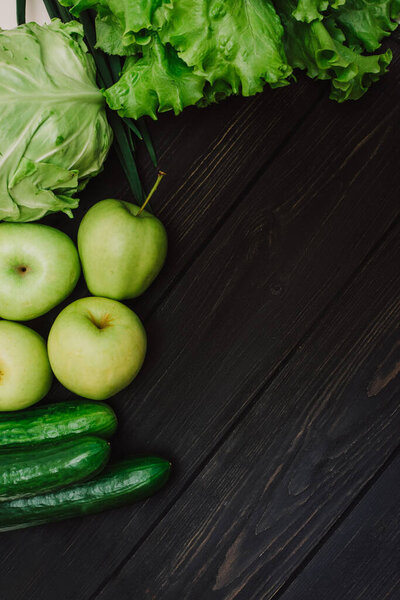 Fresh green organic vegetables and fruits in an eco reusable bag. Cucumbers, cabbage, lettuce, apples on black wooden background. Detox and green dieting. Healthy lifestyle concept. Eco life