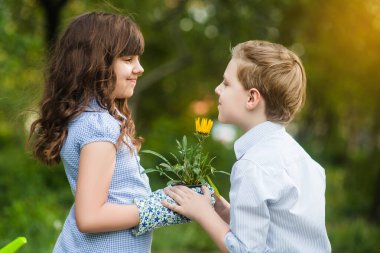 Tatlı kız ve oğlan bahçıvancılık oynuyor ve bahar bahçesinde çiçek dikiyorlar. Mutlu çocukluk
