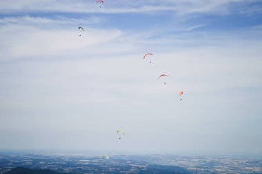 İniş yapan bir gökyüzü dalgıcının silueti. İnsanlar arka planda paraşütle süzülüyorlar. Ekstrem Hava Sporları
