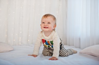 Garland ile beyaz yatakta oturup beyaz bebek çocuk gülümsedi