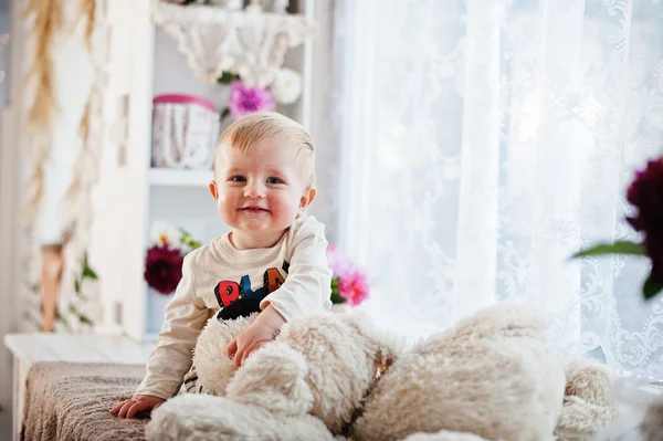 부드러운 장난감 개와 창턱에 앉아 귀여운 백인 아기 소년 — 스톡 사진