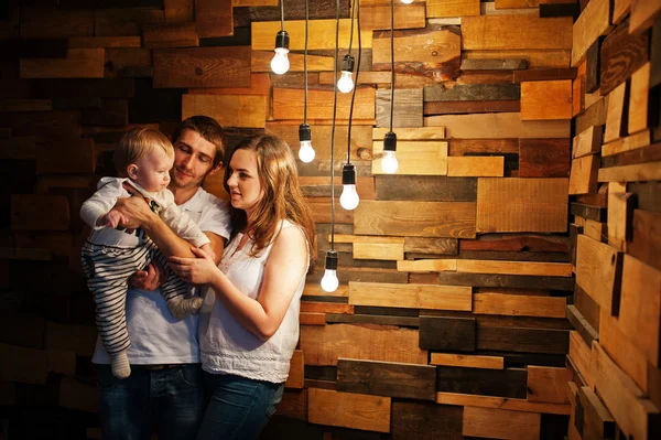 Familia con bebé niño cerca de la decoración lámparas incandescentes luz — Foto de Stock