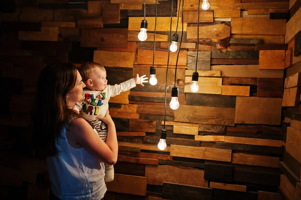 Madre con bebé niño cerca de la decoración lámparas incandescentes luz — Foto de Stock