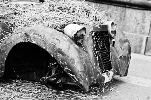 Old abandoned car with hay on engine — Stock Photo, Image