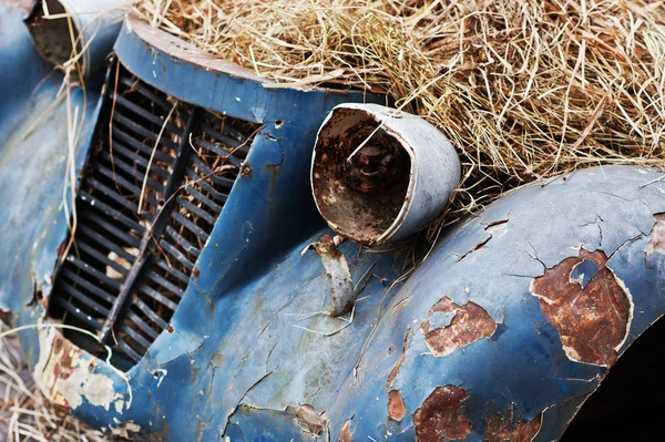 Old abandoned car with hay on engine — Stock Photo, Image