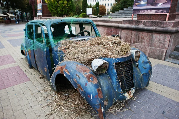 Old abandoned car with hay on engine — Stock Photo, Image