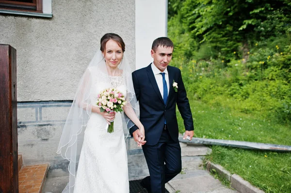 Matrimonio coppia a piedi giù per le scale per la chiesa che si tiene per mano — Foto Stock