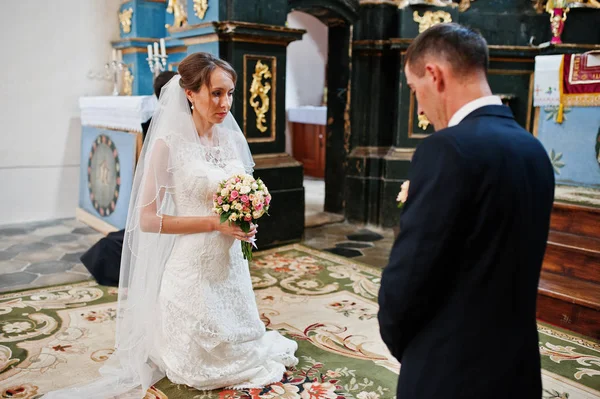 Couple de mariage agenouillé et prier à l'église lors de la cérémonie de mariage — Photo