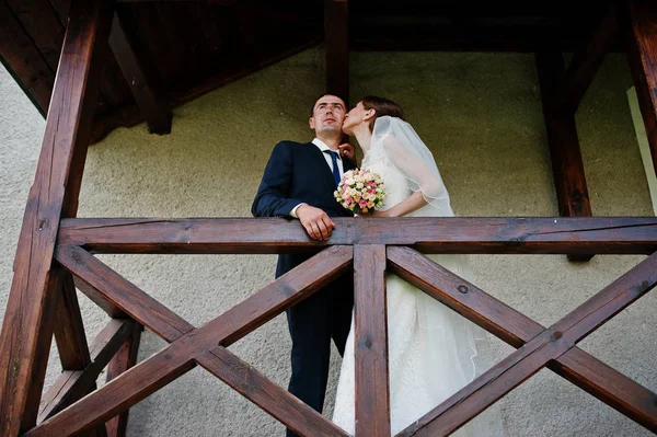 Свадебная пара остается на балконе рядом с деревянными перилами. Brid — стоковое фото
