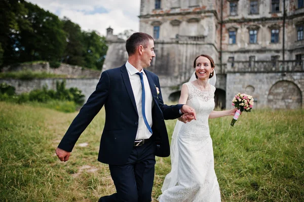 Couple de mariage courant tenant les mains arrière-plan château . — Photo