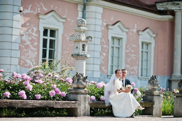 Wedding couple sitting on bench background peonies garden — Stock Photo, Image