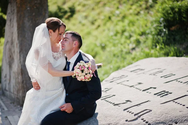 Matrimonio coppia seduta su pietra monumento con vecchia iscrizione — Foto Stock