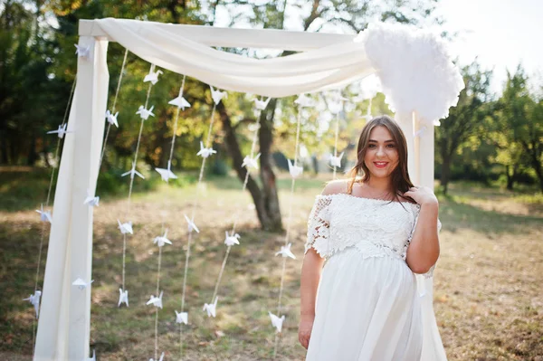 Mujer embarazada feliz en vestido blanco arco de decoración de fondo o —  Fotos de Stock