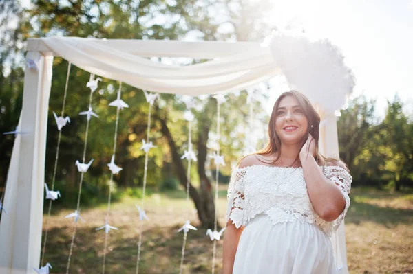 Gelukkig zwangere vrouw op witte jurk achtergrond decoratie arch o — Stockfoto