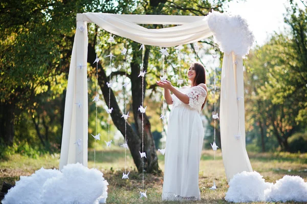 Mujer embarazada feliz en vestido blanco arco de decoración de fondo o — Foto de Stock