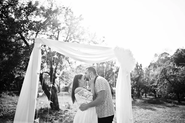 Feliz casal grávida ficar abraçando e amando perto arco decoração em — Fotografia de Stock
