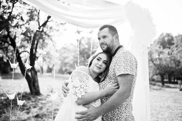 Feliz embarazada pareja estancia abrazo y amoroso cerca de arco de decoración en —  Fotos de Stock