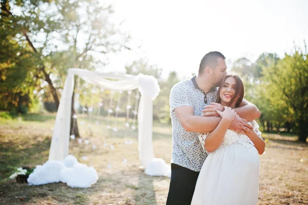 Feliz embarazada pareja estancia abrazo y amoroso cerca de arco de decoración en —  Fotos de Stock