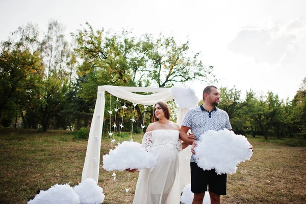 Felice coppia incinta rimanere vicino arco di arredamento in giardino e tenere d — Foto Stock