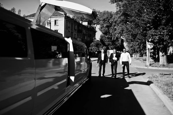 Három jóképű srácok besétál luxus limuzinnal biztosítja. A vőlegény be — Stock Fotó