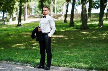 Trendy sakallı adam damat papyon ile park üzerinde poz verdi..
