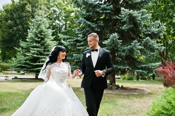 Pasangan menikah ceria berjalan bergandengan tangan di kebun hijau co — Stok Foto