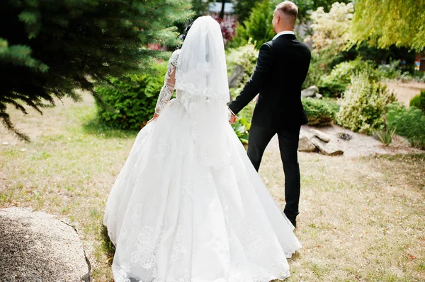 Back view of walking wedding couple at garden of courtyard. — Stock Photo, Image