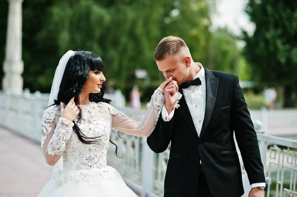 Csodálatos esküvő házaspár sétáló a hídon. Vőlegény csók keze bri — Stock Fotó