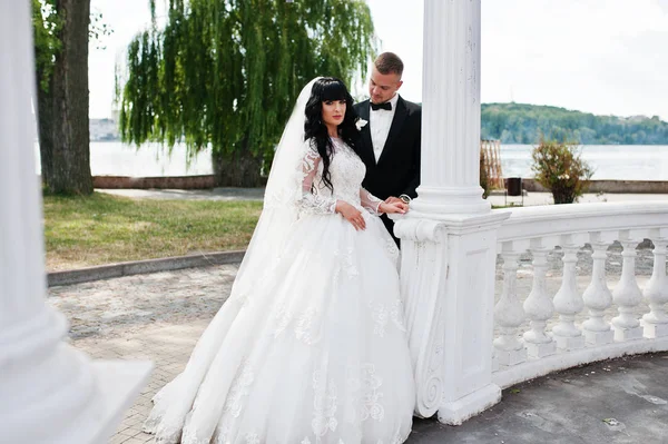 Casal magnífico perto de colunas brancas de arco de amor . — Fotografia de Stock