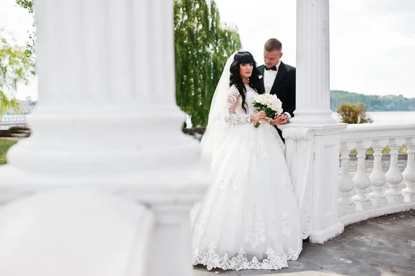 Nádherné svatební pár poblíž bílé sloupce oblouku lásky. — Stock fotografie