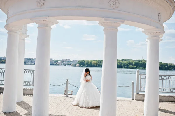 Noiva sob colunas brancas monumento fundo lago no casamento ensolarado — Fotografia de Stock