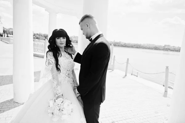 Excelente pareja de boda bajo columnas blancas monumento fondo la —  Fotos de Stock