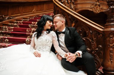 Büyük r zengin ahşap merdivenlerde oturan büyüleyici Düğün çifti