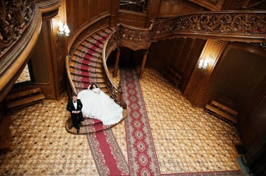 Büyük r zengin ahşap merdivenlerde oturan büyüleyici Düğün çifti