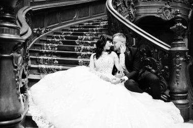 Büyük r zengin ahşap merdivenlerde oturan büyüleyici Düğün çifti