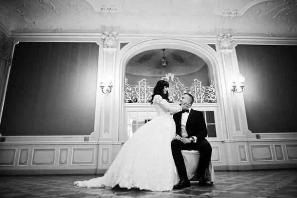 Magnificent wedding couple sitting on chair on royal room with m — Stock Photo, Image