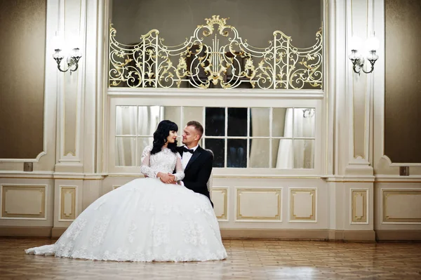 Великолепная свадебная пара, сидящая на стуле в королевской комнате с m — стоковое фото
