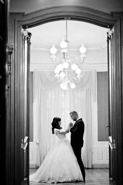 Rich wedding couple at royal room with golden lamp on the ceilin — Stock Photo, Image