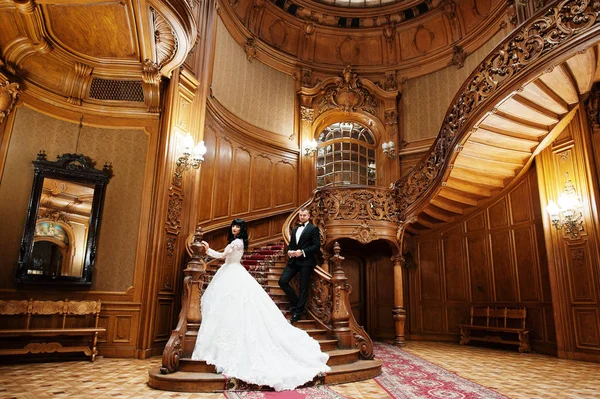 Casal incrível em grandes escadas de madeira no palácio rico . — Fotografia de Stock