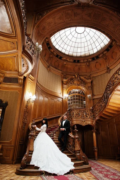 Casal incrível em grandes escadas de madeira no palácio rico . — Fotografia de Stock