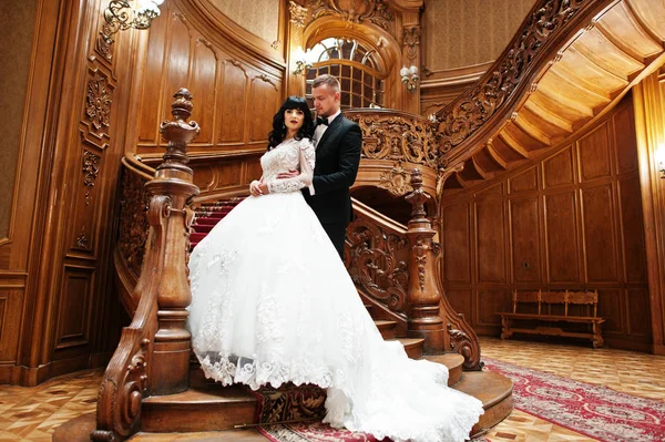 Casal incrível em grandes escadas de madeira no palácio rico . — Fotografia de Stock