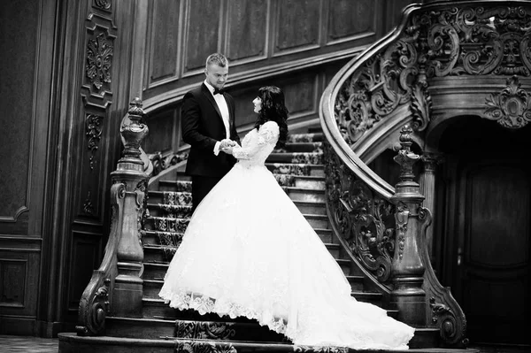 Amazing wedding couple on big wooden stairs at rich palace. — Stock Photo, Image